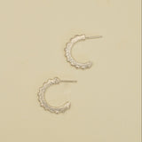 Pair of silver hoop earrings on a beige background