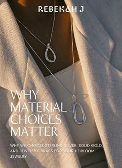 A woman wearing two layered silver pendants over a cream colored top, and a blazer