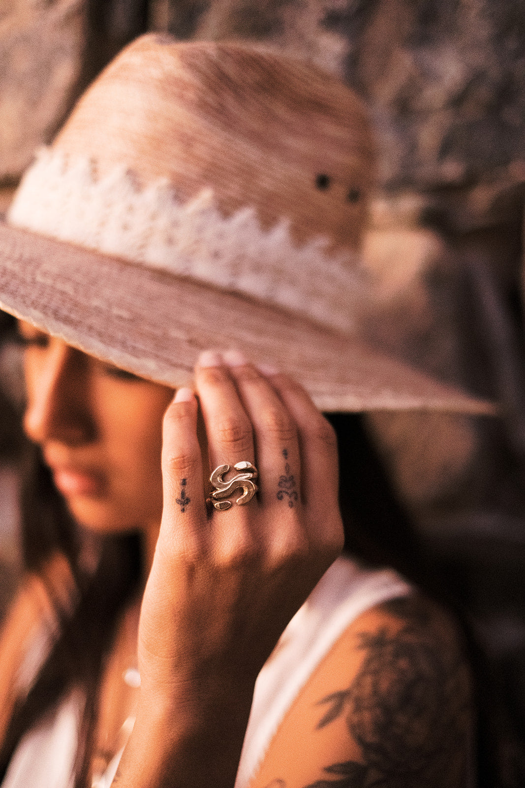 Woman wearing stacked Ebb rings and holding her hat