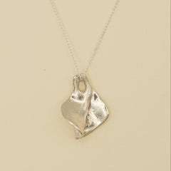 Silver necklace with a unique pendant on a beige background