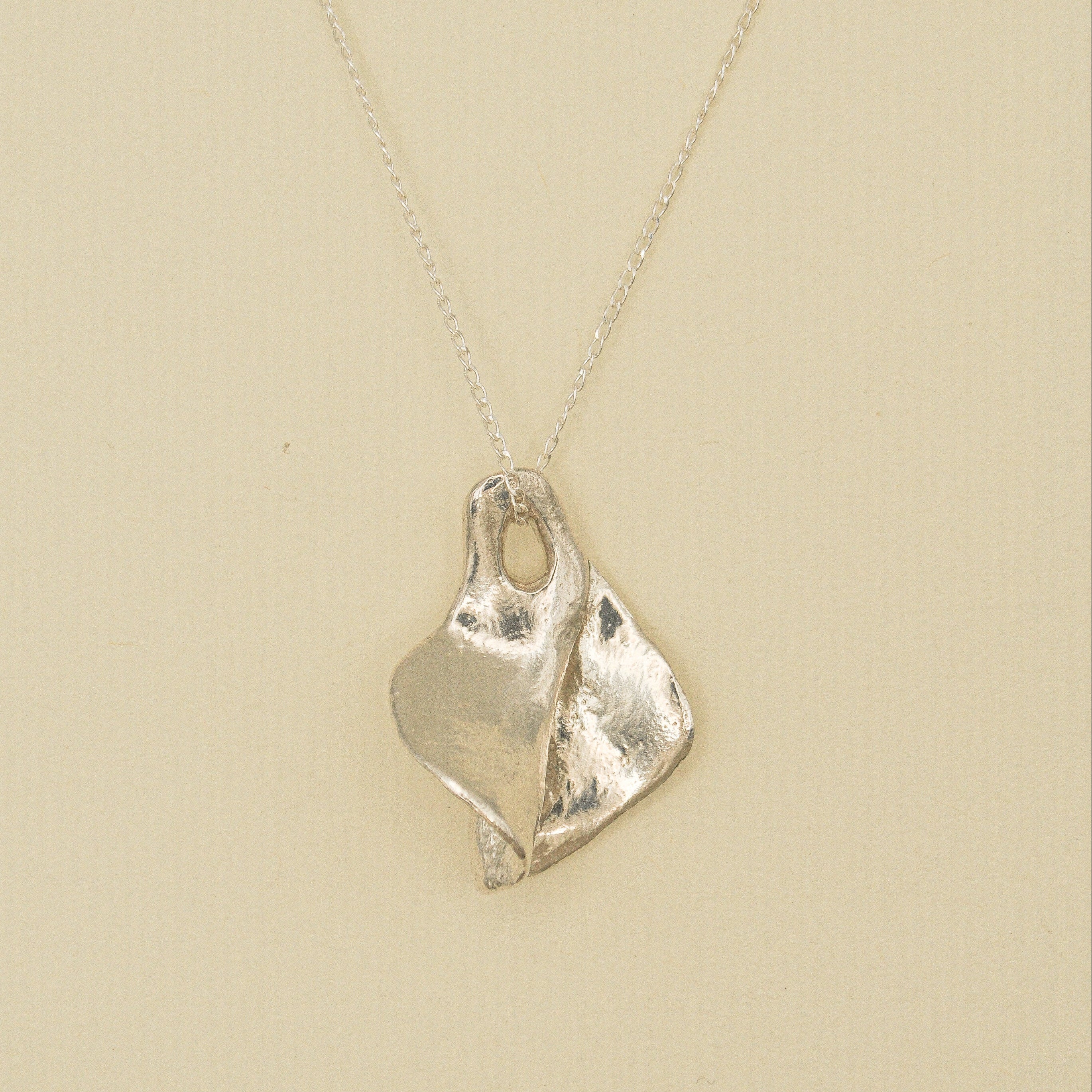 Silver necklace with a unique pendant on a beige background