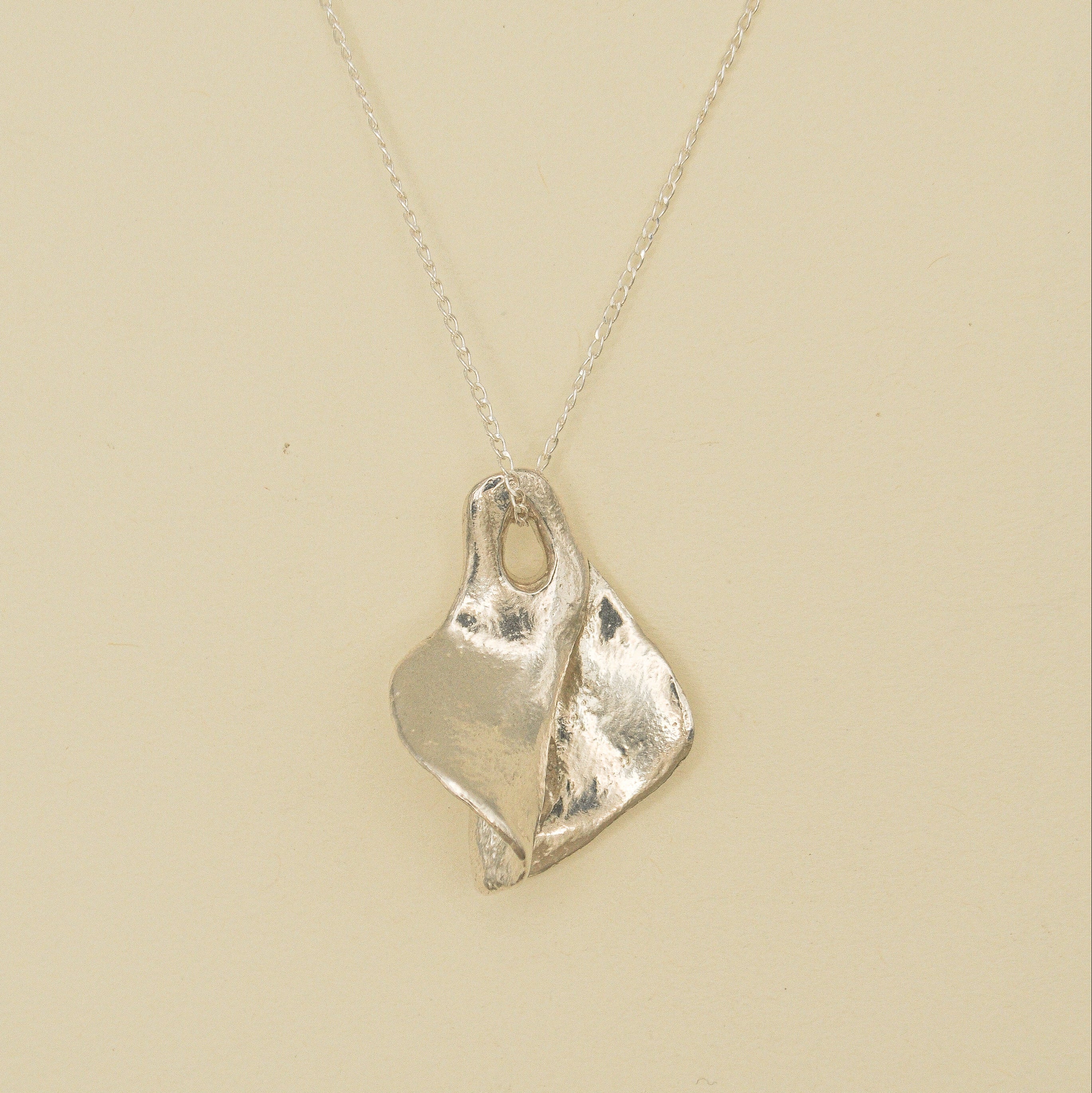 Silver necklace with a unique pendant on a beige background