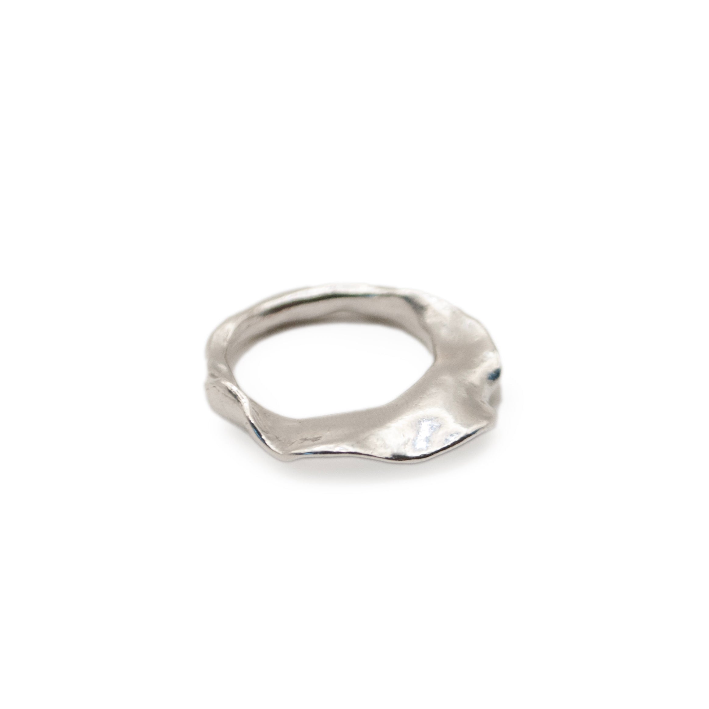 A silver-colored flat oyster-shaped ring, hand carved and lost wax cast, on a white background.