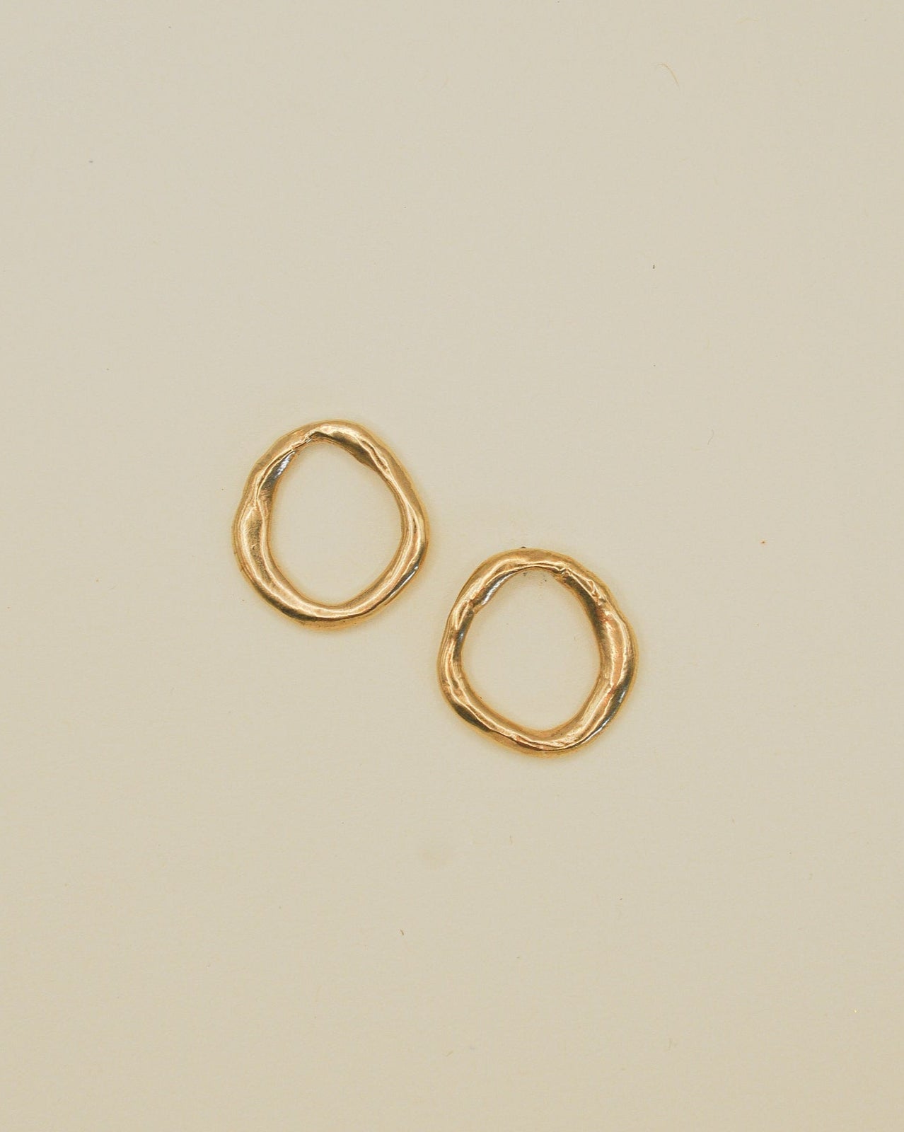 Gold hoop earrings on a beige background