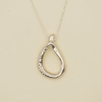 Silver teardrop pendant necklace on a beige background