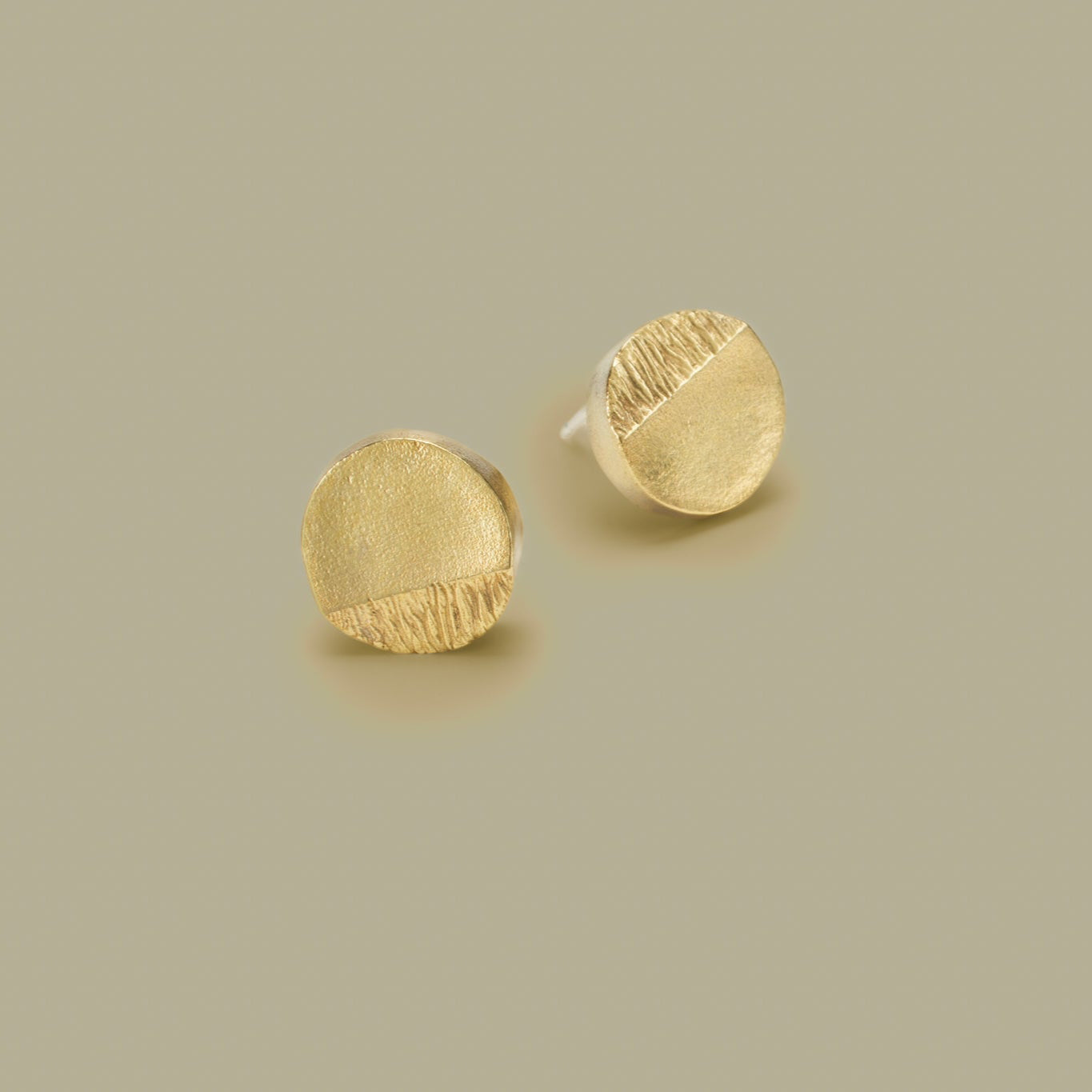 Pair of gold stud earrings on a beige background