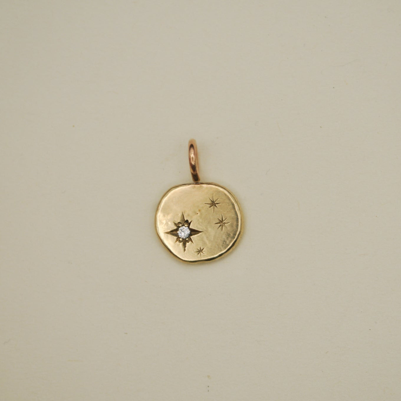 Gold pendant with star design on a beige background