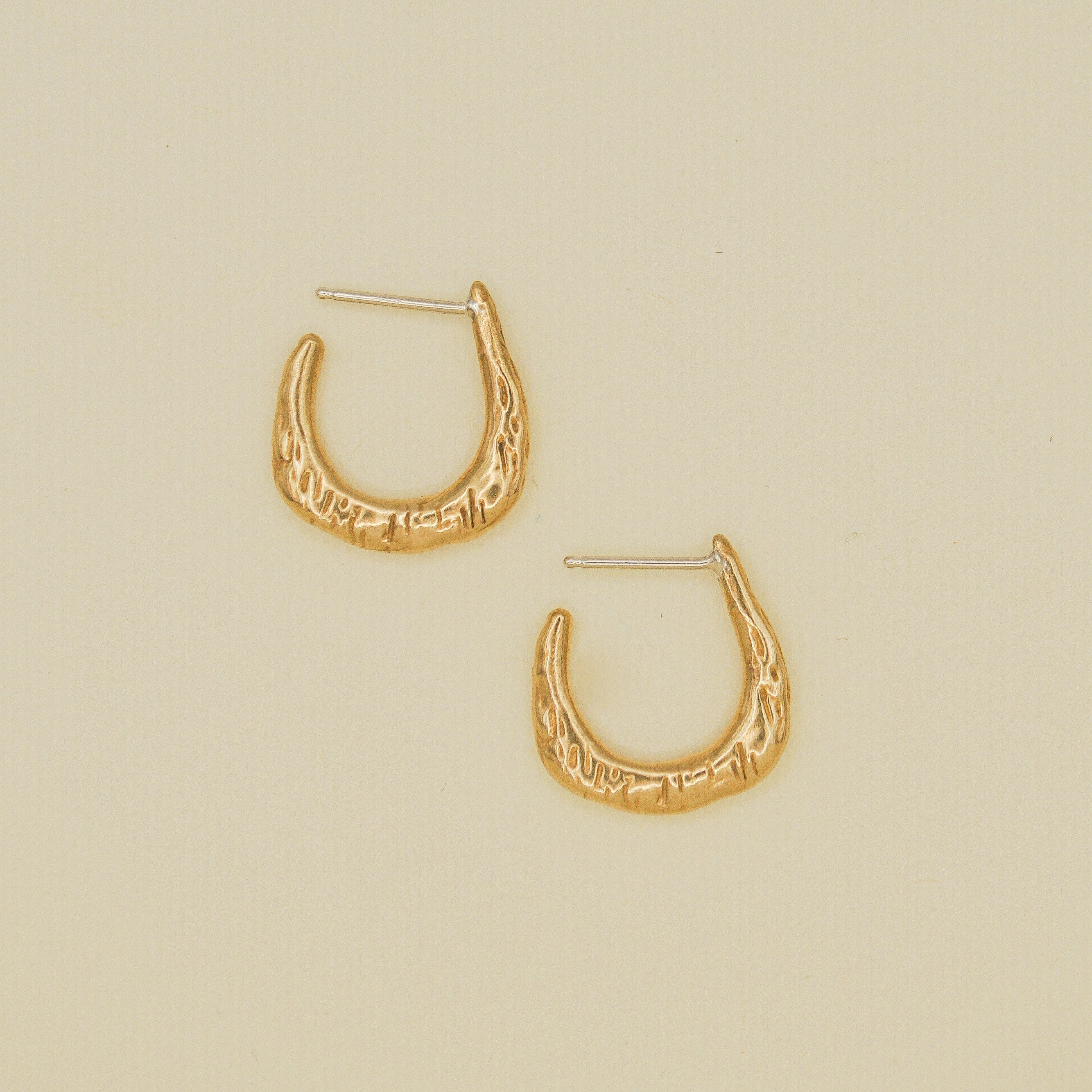 Gold hoop earrings on a beige background