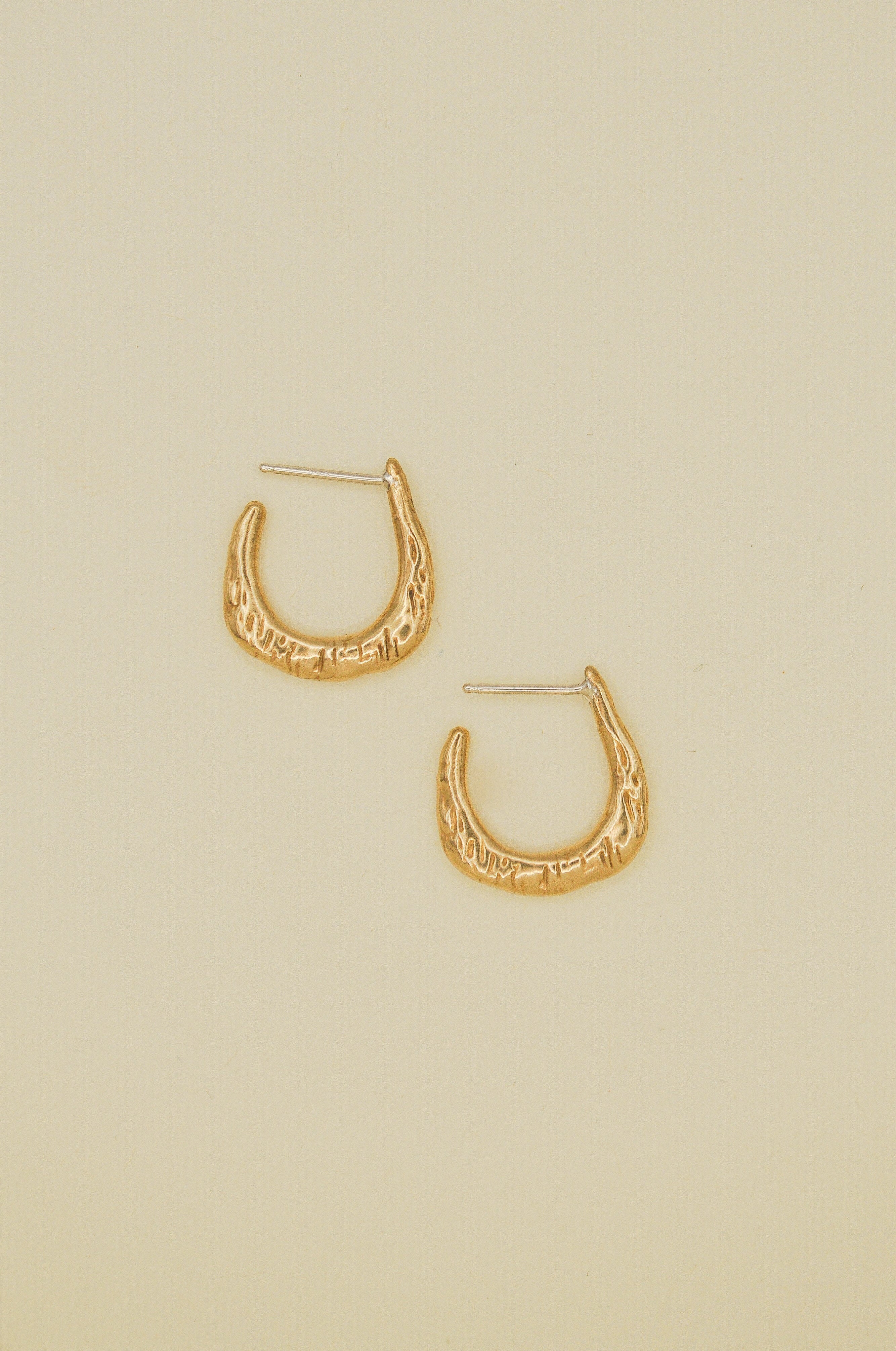 Gold hoop earrings on a beige background