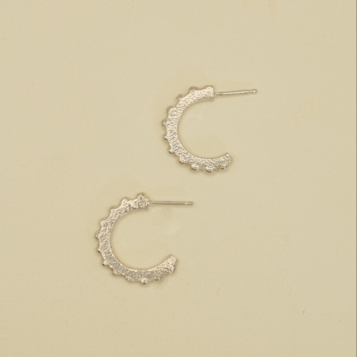 Pair of silver hoop earrings on a beige background