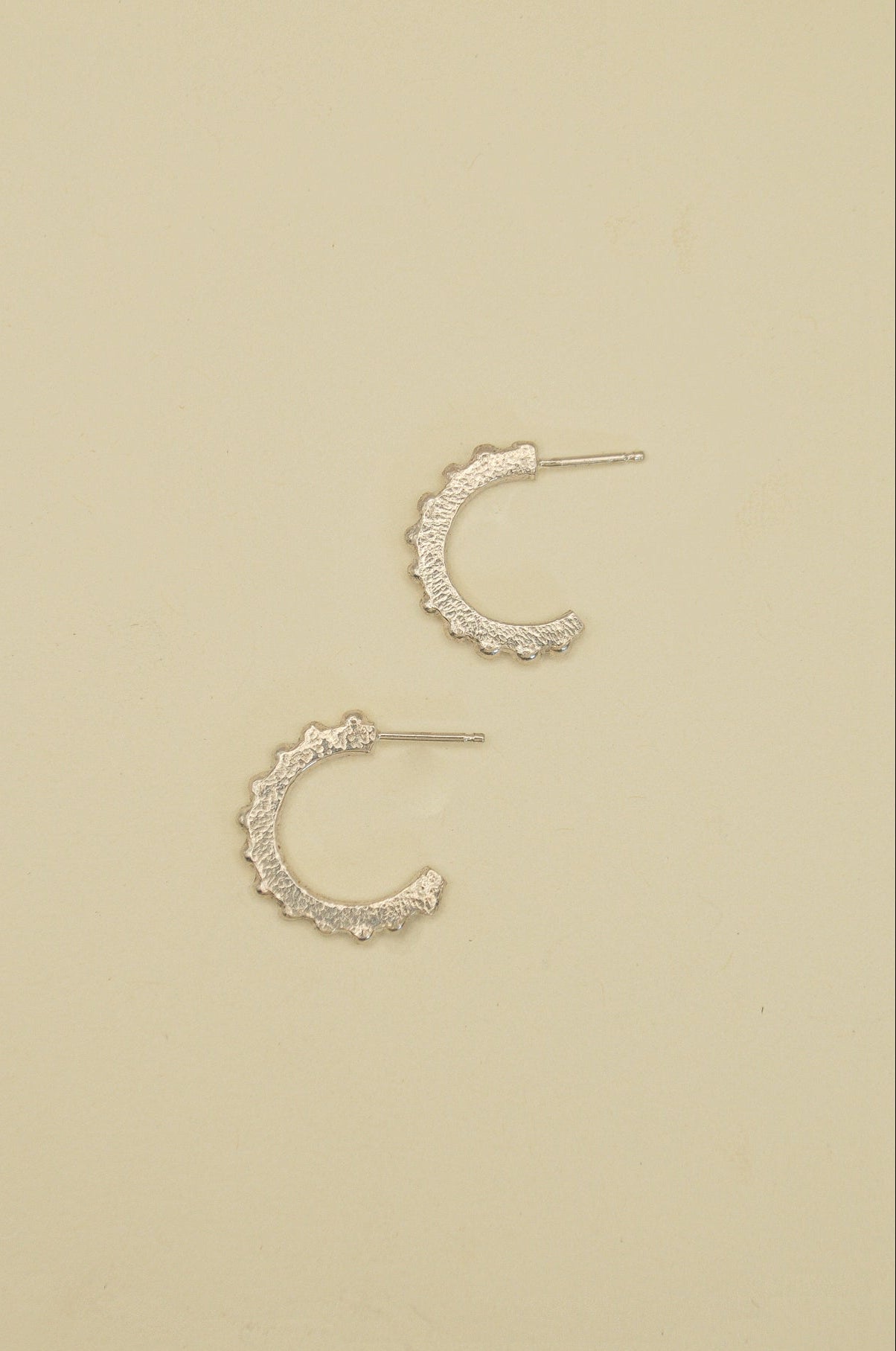 Pair of silver hoop earrings on a beige background
