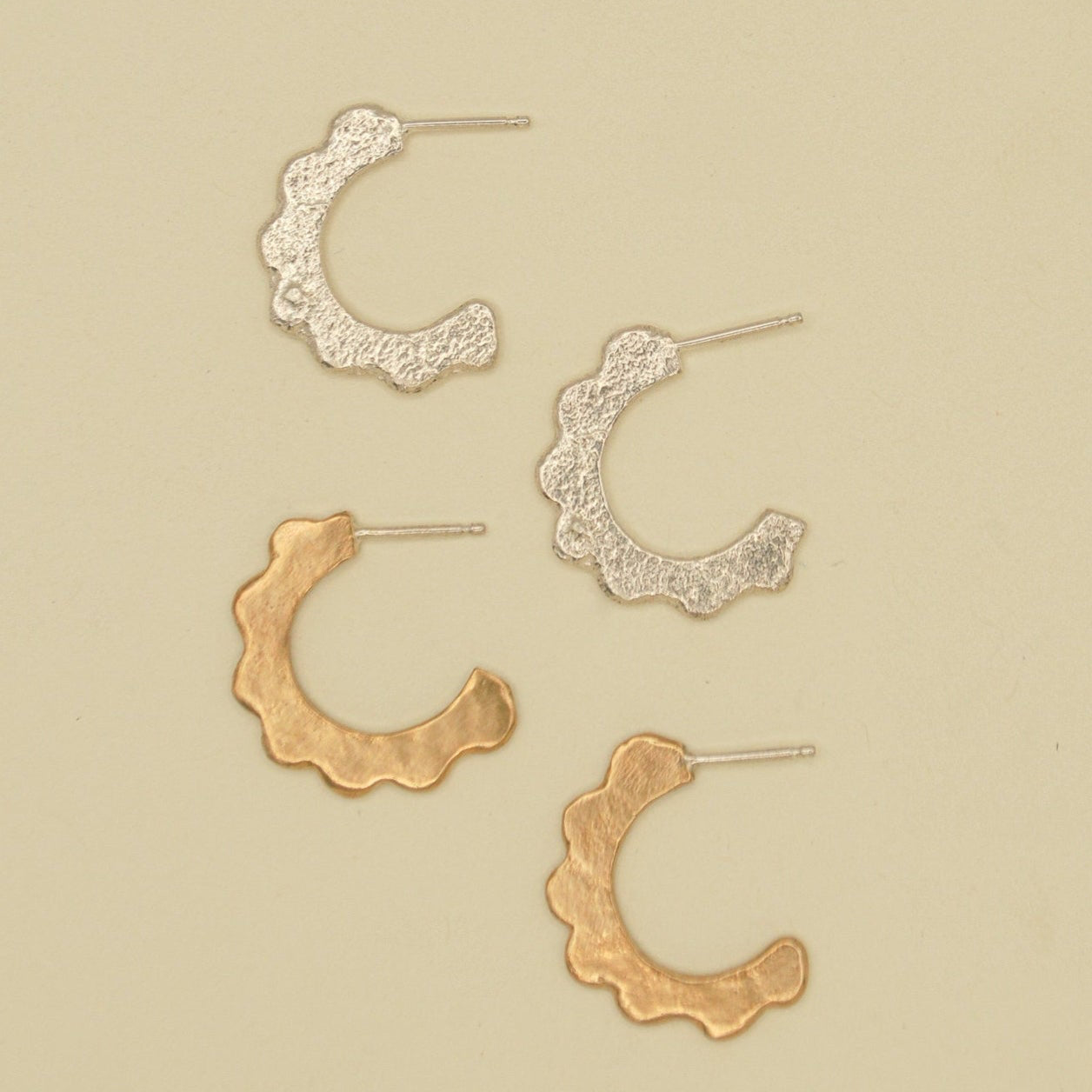 Set of gold and silver scalloped hoop earrings on a beige background. sand cast by hand