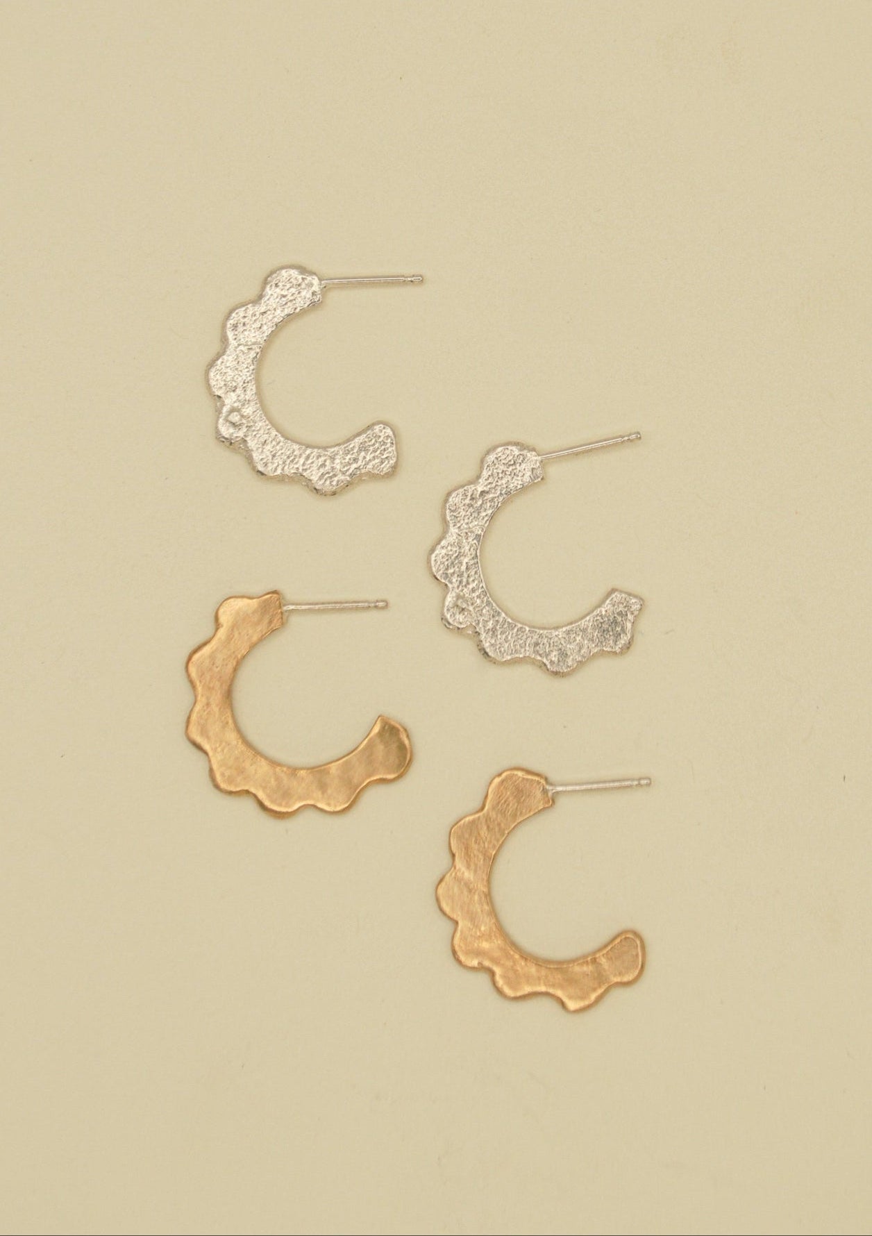 Set of gold and silver scalloped hoop earrings on a beige background. sand cast by hand